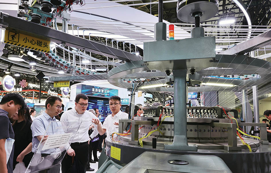 2025年7月26日，参观者在一个依托大模型数据打造的星辰纺织智能体展品旁交流讨论 方喆摄/本刊