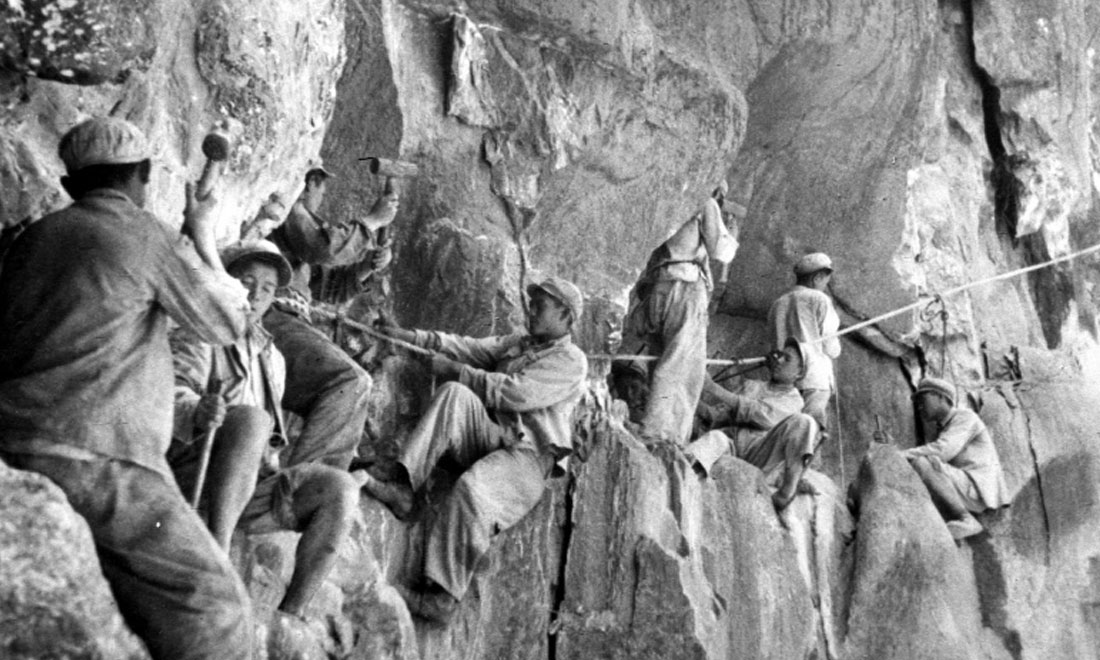 1954年，修筑康藏公路的解放軍戰(zhàn)士們?cè)谂瓋砂兜膽已露副谏媳偕街?。新華社稿 李萬(wàn)春、張加里攝